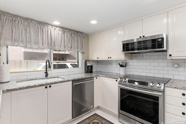 kitchen with a sink, tasteful backsplash, appliances with stainless steel finishes, and white cabinets