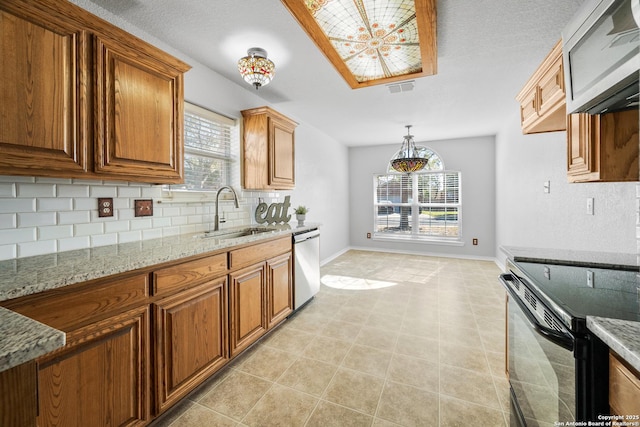 kitchen with visible vents, brown cabinets, a sink, appliances with stainless steel finishes, and decorative backsplash