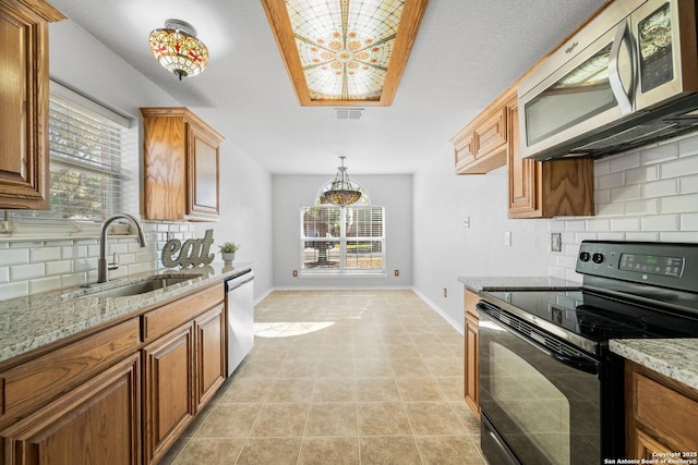 kitchen featuring a sink, stainless steel appliances, a chandelier, and brown cabinetry