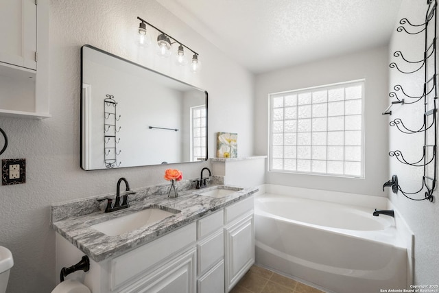 full bathroom featuring a sink, a textured wall, a garden tub, and a textured ceiling