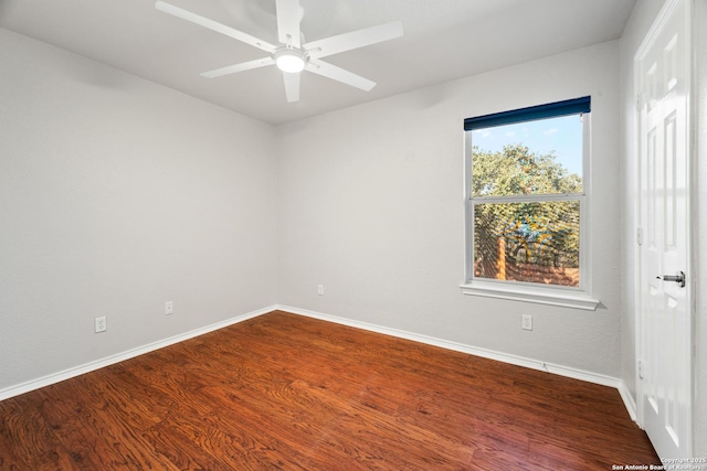 empty room with baseboards, dark wood finished floors, and a ceiling fan