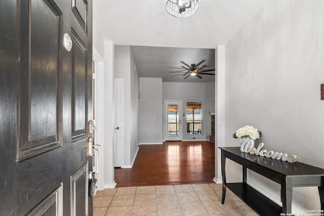 entryway with light tile patterned floors, a ceiling fan, and baseboards