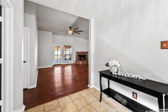 hall featuring lofted ceiling, light tile patterned flooring, and baseboards