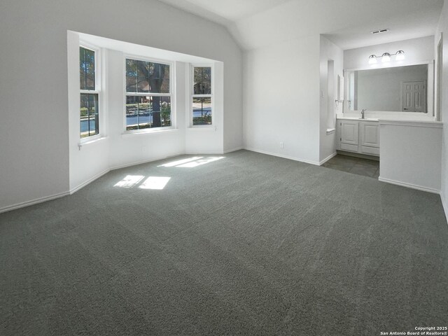 unfurnished bedroom featuring carpet, baseboards, lofted ceiling, a sink, and connected bathroom