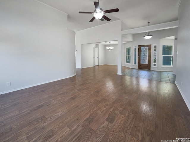 unfurnished living room featuring ceiling fan with notable chandelier, ornamental molding, baseboards, and wood finished floors