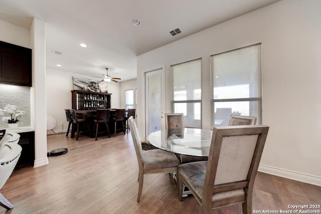 dining room featuring wood finished floors, visible vents, baseboards, recessed lighting, and a bar