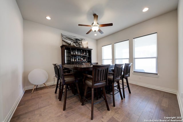 dining room featuring a bar, recessed lighting, wood finished floors, and baseboards