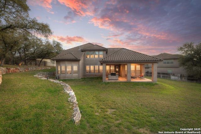 back of house featuring a yard, a tile roof, a patio, and fence