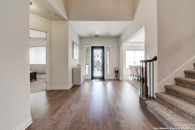 foyer entrance with stairs, visible vents, baseboards, and dark wood-style flooring