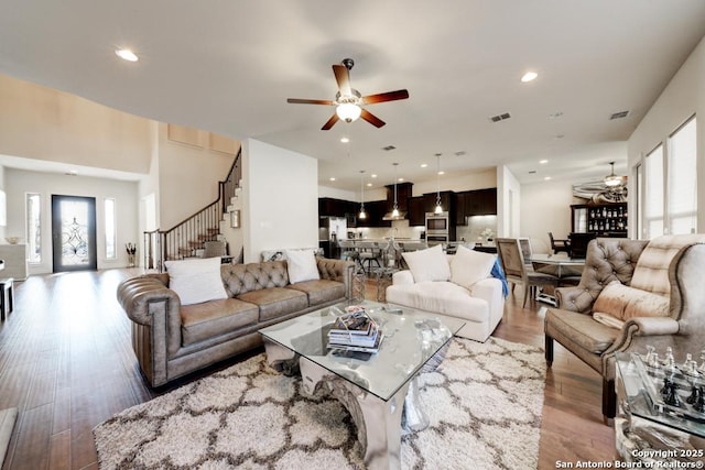 living room featuring visible vents, a ceiling fan, wood finished floors, recessed lighting, and stairs