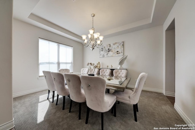 carpeted dining area featuring a tray ceiling, baseboards, and an inviting chandelier