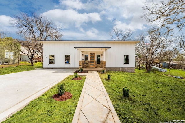 modern farmhouse style home featuring stone siding, board and batten siding, covered porch, and a front lawn