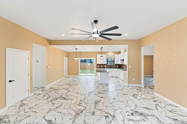 unfurnished living room featuring recessed lighting, baseboards, marble finish floor, and a ceiling fan