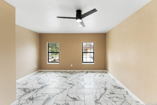 spare room with a ceiling fan, baseboards, and marble finish floor