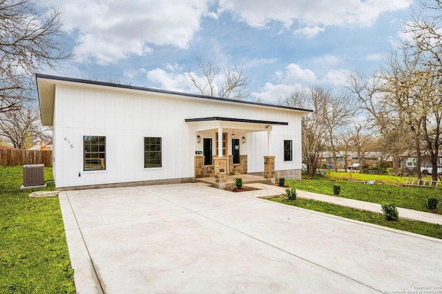 modern inspired farmhouse with board and batten siding, fence, central air condition unit, a porch, and a front yard