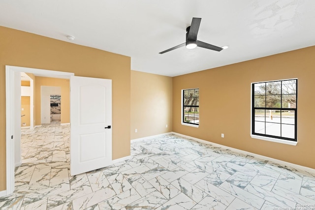 empty room with plenty of natural light, marble finish floor, and baseboards