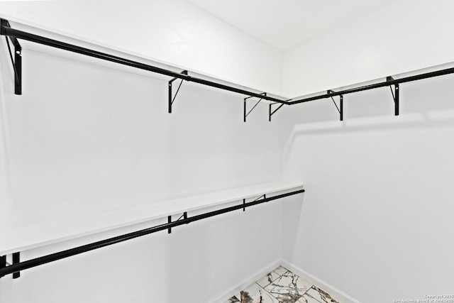 walk in closet featuring marble finish floor