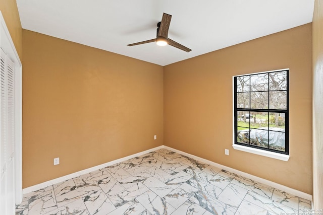 empty room with a ceiling fan, baseboards, and marble finish floor