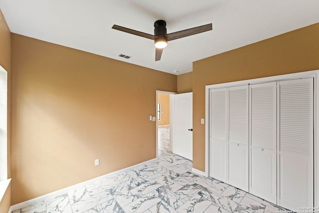 bedroom with visible vents, marble finish floor, a ceiling fan, a closet, and baseboards