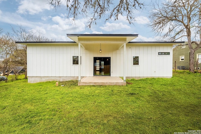 back of property with a yard, board and batten siding, and a patio area