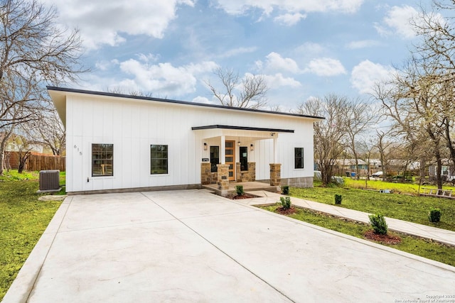 view of front of property with a front lawn, central AC unit, covered porch, and board and batten siding