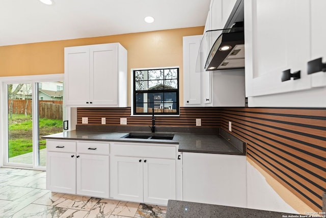 kitchen featuring dark countertops, marble finish floor, ventilation hood, and a sink