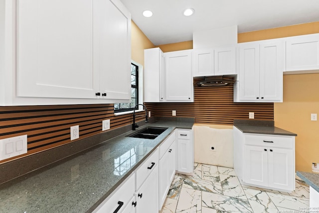 kitchen with dark stone countertops, recessed lighting, a sink, white cabinets, and marble finish floor