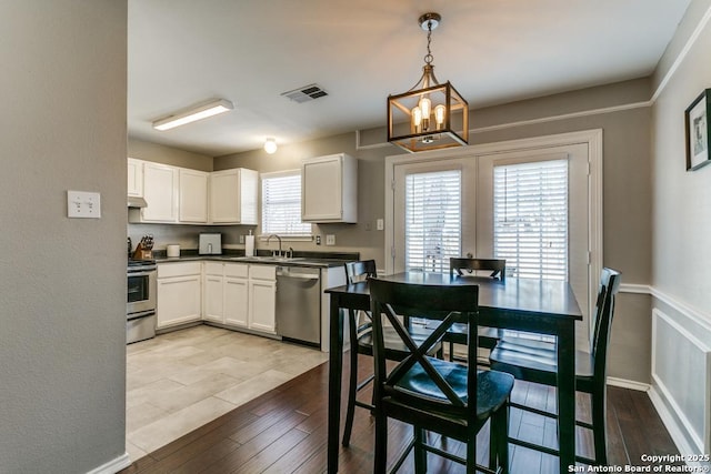 kitchen with visible vents, a sink, wood finished floors, stainless steel appliances, and white cabinets