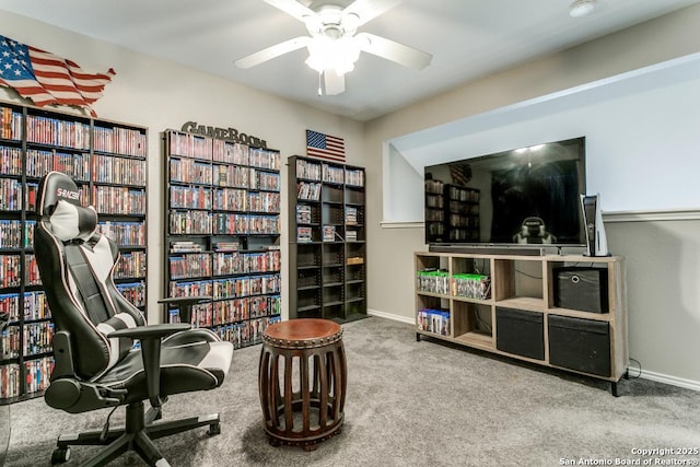 sitting room with carpet flooring, wall of books, and baseboards