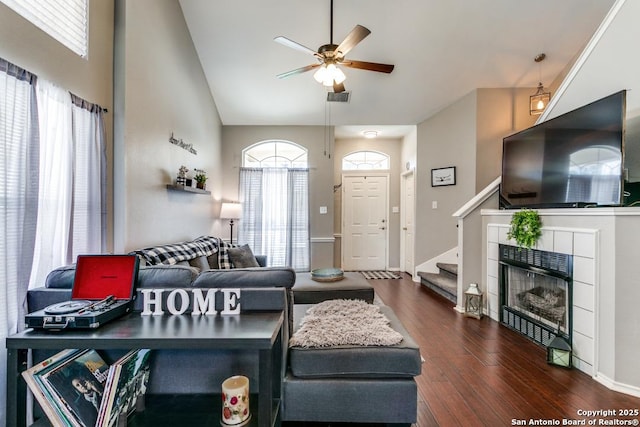 living room featuring stairway, wood finished floors, visible vents, ceiling fan, and a tiled fireplace