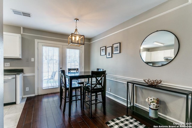 dining room featuring a wainscoted wall, a notable chandelier, wood finished floors, and visible vents