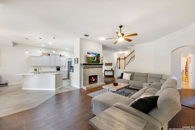 14019 Tahoe Vis, San Antonio, TX 78253 - living area with visible vents, arched walkways, a ceiling fan, light wood finished floors, and a tile fireplace