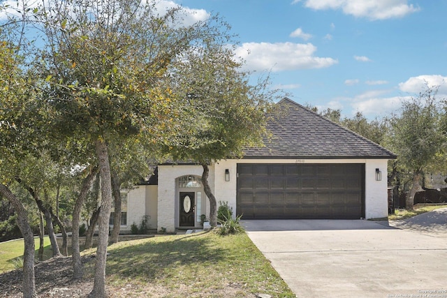 view of front of property featuring a garage, driveway, a front lawn, and a shingled roof