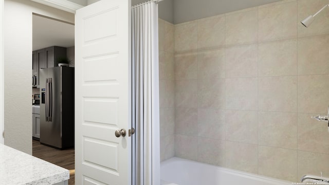 bathroom featuring wood finished floors and  shower combination