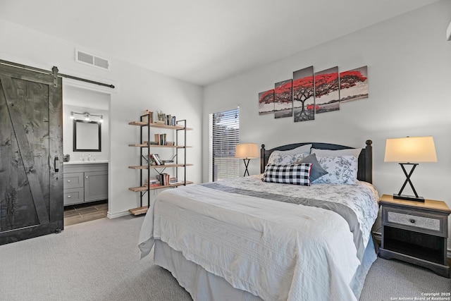 217 T Bar M # B21, New Braunfels, TX 78132 - bedroom featuring visible vents, ensuite bath, a sink, a barn door, and carpet flooring