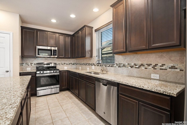 12604 Brite Rnch, San Antonio, TX 78245 - kitchen with light stone countertops, a sink, decorative backsplash, dark brown cabinetry, and stainless steel appliances