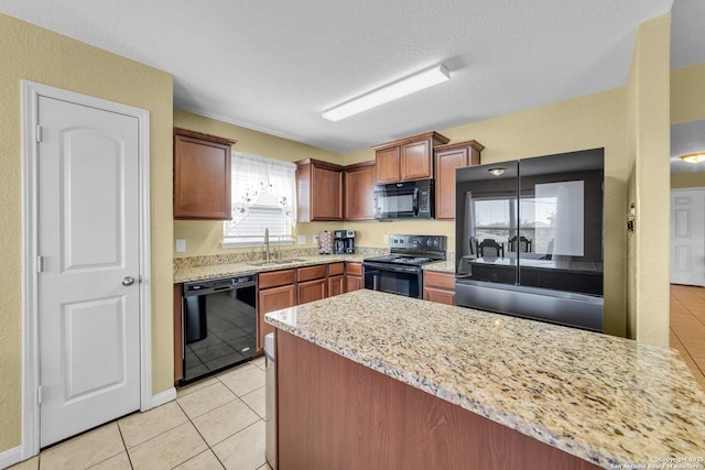 kitchen featuring light tile patterned floors, a peninsula, a textured ceiling, black appliances, and a sink