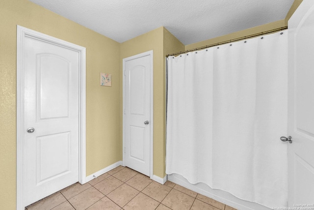 bathroom with tile patterned floors, baseboards, and a textured ceiling