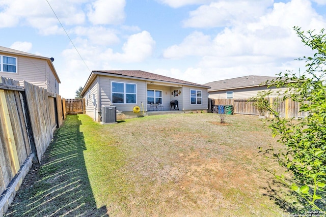 rear view of property with a yard, a fenced backyard, and central AC