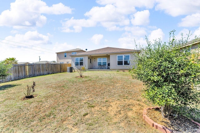 rear view of house featuring a yard, fence, and central AC