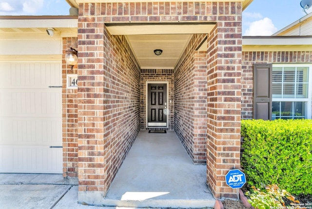 view of exterior entry with brick siding and a garage