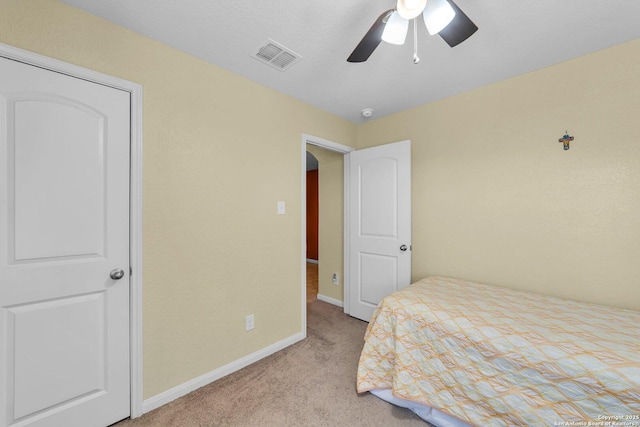 bedroom featuring visible vents, light colored carpet, baseboards, and ceiling fan