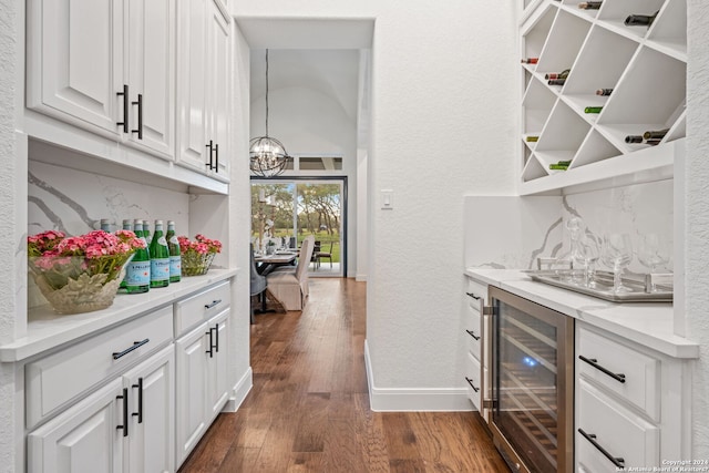 bar featuring decorative backsplash, dark wood-type flooring, an inviting chandelier, and beverage cooler