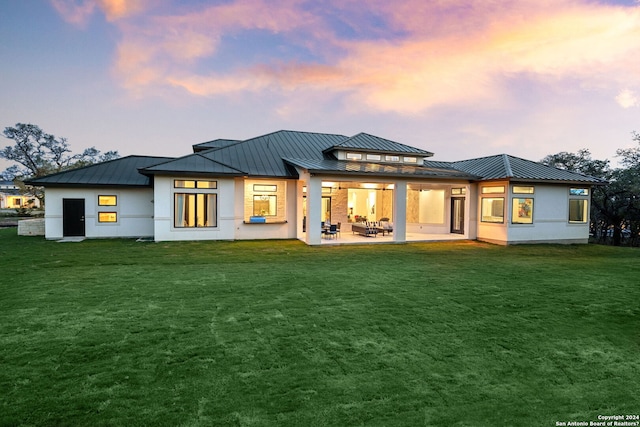 rear view of house with metal roof, a patio, a yard, and a standing seam roof