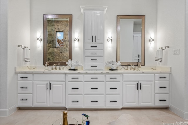 bathroom with double vanity, baseboards, tile patterned floors, and a sink