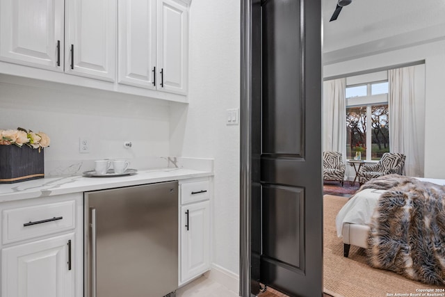 kitchen with baseboards, light stone countertops, high quality fridge, and white cabinets