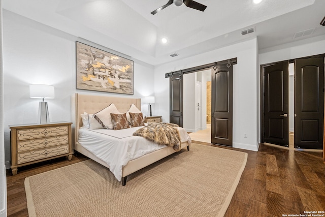 bedroom featuring a barn door, visible vents, and dark wood-style flooring