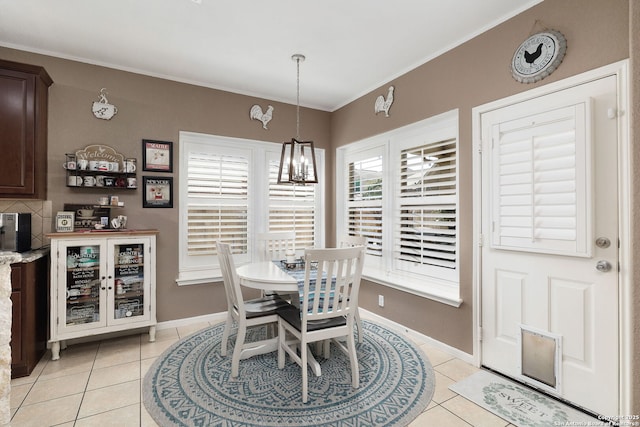 dining room featuring an inviting chandelier, crown molding, light tile patterned floors, and baseboards