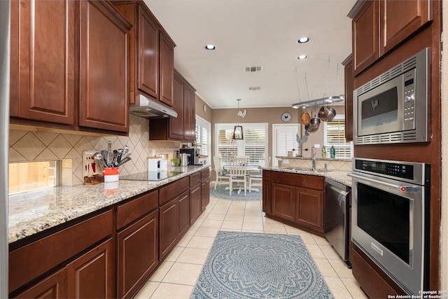 kitchen featuring visible vents, under cabinet range hood, tasteful backsplash, stainless steel appliances, and light tile patterned flooring