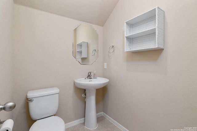 bathroom with tile patterned floors, toilet, baseboards, and a sink